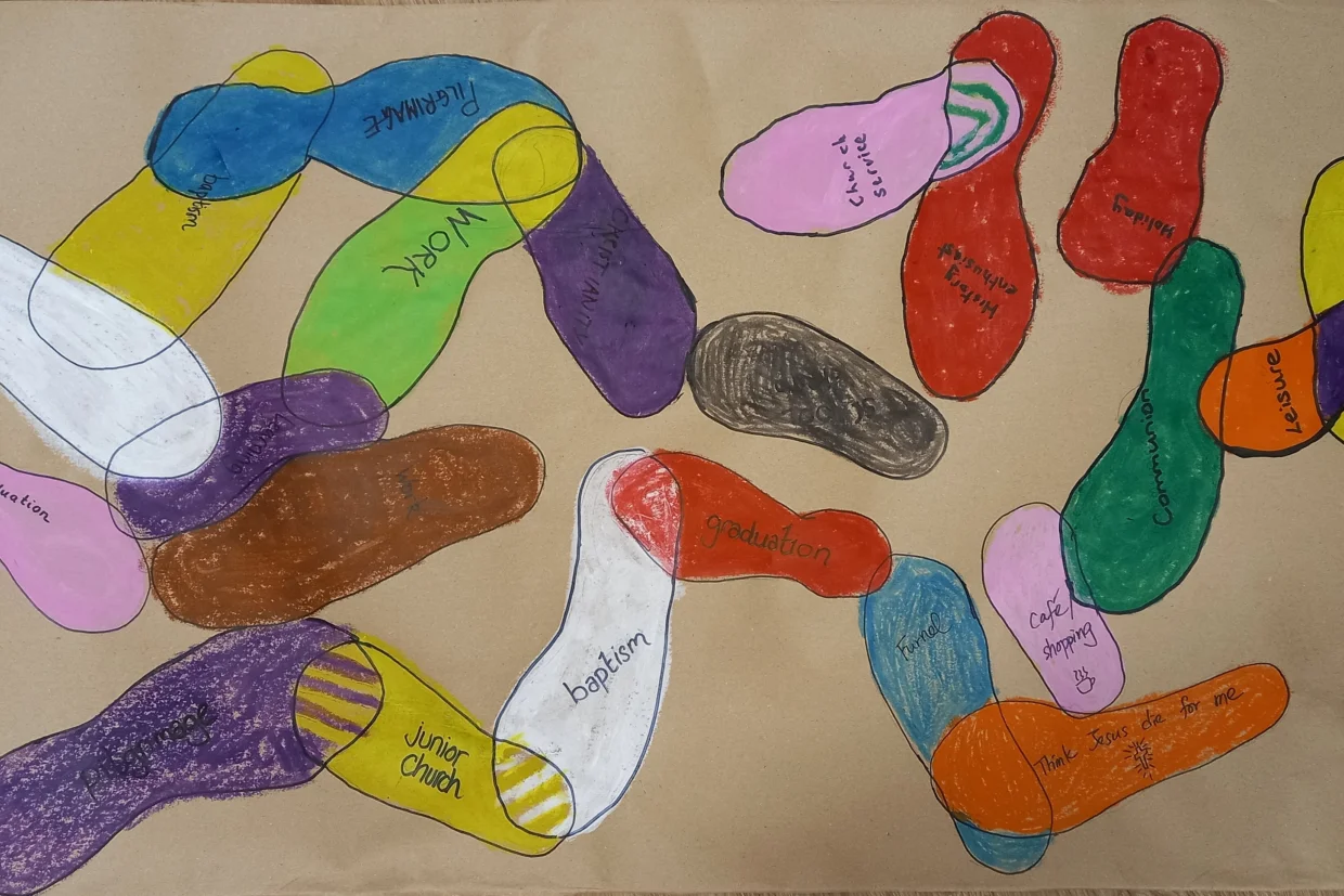 This image shows many colourful footprint shapes overlapping on a sandy background.