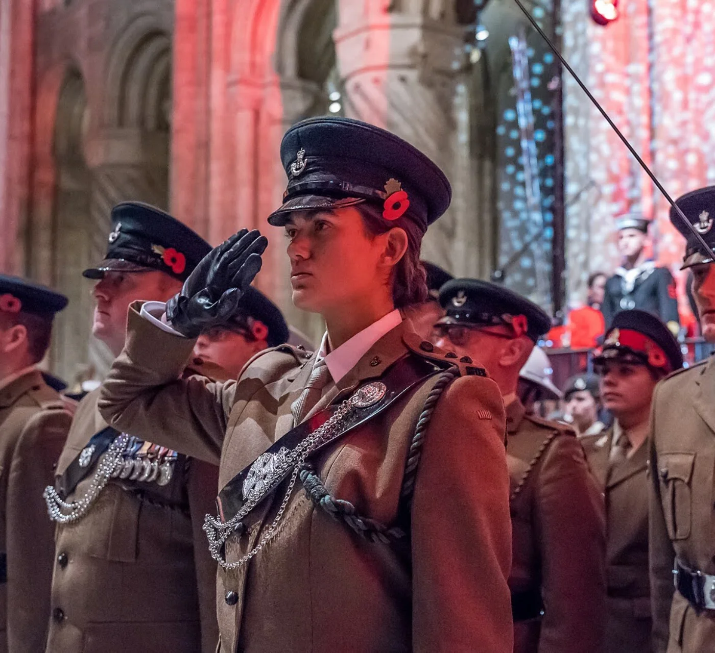 Woman in army uniform saluting, as poppy's fall on remembrance Sunday